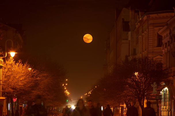 Street of the night city in Ukraine against the background of the rising moon - Photo, Image