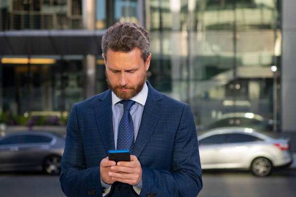 Portrait of businessman standing in a office. Businessman talking on phone. Portrait of cheerful Business man office worker talking on mobile phone while standing near modern office. - Foto, Imagen