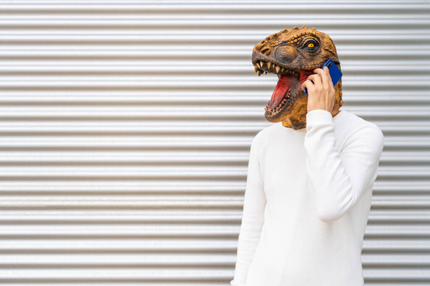 Uomo ritratto indossando maschera testa di dinosauro parlando al telefono - Foto, immagini