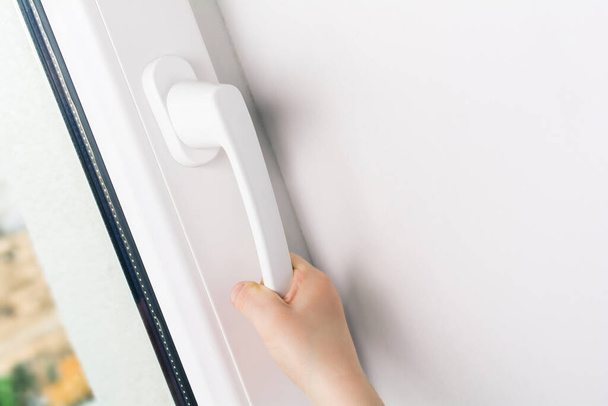 Child Hand Trying To Open A Window Handle Of A Closed White Window - Prevent Child Hazard Concept - Foto, Imagem