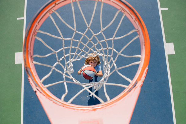 Angle view from on top of child playing basketball on playground. - Φωτογραφία, εικόνα