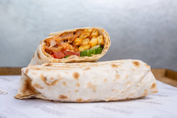 doner in pita bread with chicken and vegetables in a cut. - Фото, изображение