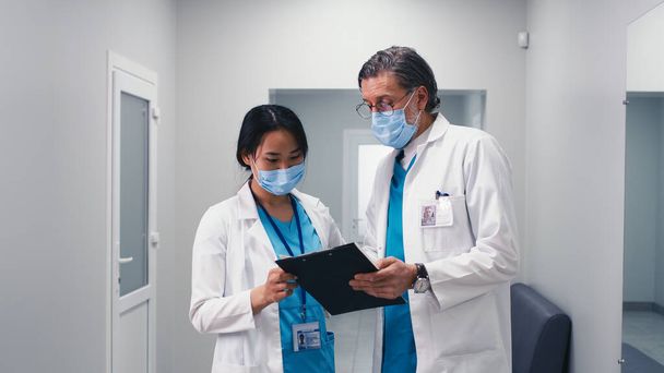 Различные врачи обсуждают данные в коридоре - Фото, изображение
