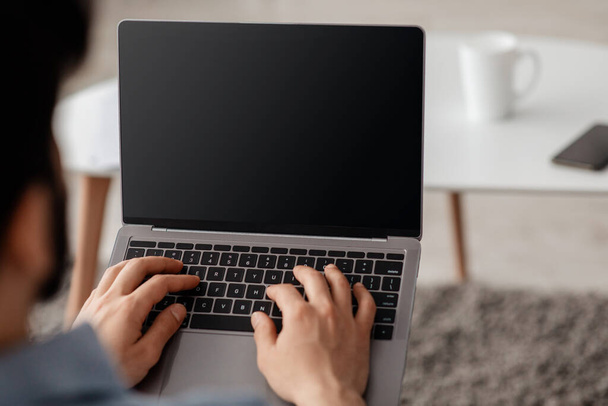 Felismerhetetlen férfi szabadúszó laptopot használ üres képernyővel, online dolgozik és hirdetési internetes honlapján - Fotó, kép