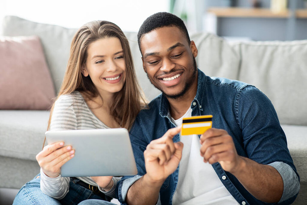 E-commerce Concept. Interraciale paar winkelen Online met digitale tablet en creditcard - Foto, afbeelding