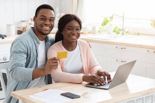 Pagamentos online. Retrato de jovens cônjuges africanos com laptop e cartão de crédito - Foto, Imagem