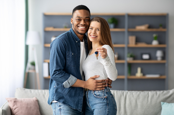 Šťastný mladý multiraciální pár držící doma klíče a objímající - Fotografie, Obrázek