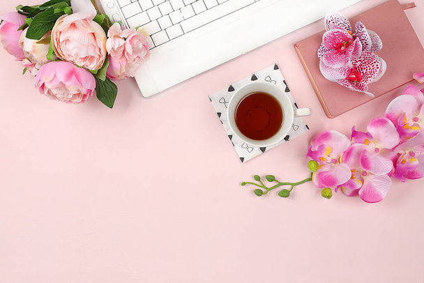 Modern woman working desk, home office. Computer, a cup of tea, macaroons and spring orchid flowers on a light table. Business minimal concept, home comfort, top view, flat lay, place for text, selective focus - Foto, imagen