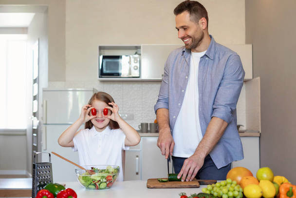 Papá y su hija se divierten cocinando juntos en la cocina moderna - Foto, Imagen