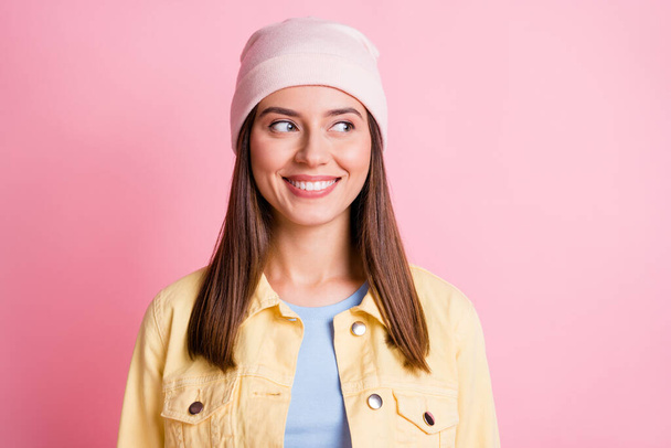 Photo of sweet shiny young woman dressed casual yellow clothes cap looking empty space smiling isolated pink color background - Photo, image