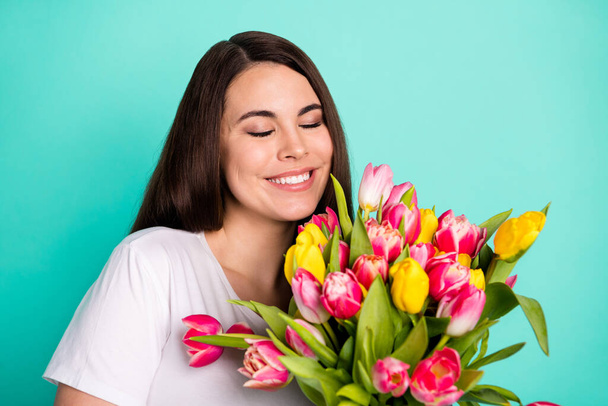 Photo of young attractive woman happy positive smile enjoy aroma spring flowers tulips isolated over turquoise color background - Fotoğraf, Görsel