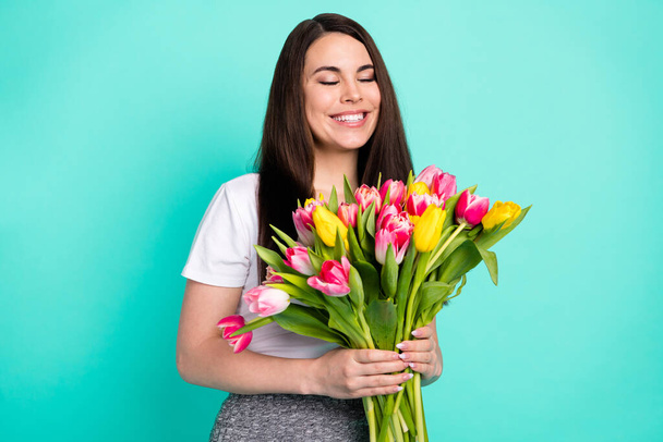 Photo of cheerful young girl happy positive smile birthday gift flowers bouquet isolated over turquoise color background - Foto, Imagen