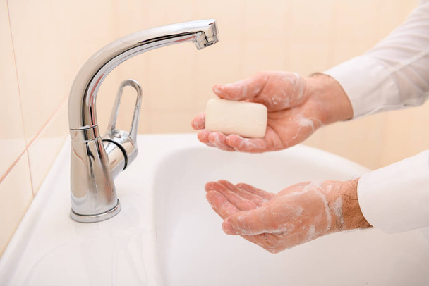 Händewaschen mit Seife oder Gel unter fließendem Wasser im Waschbecken, Sauberkeit und Hygiene, Männerhände in weißem Hemd - Foto, Bild