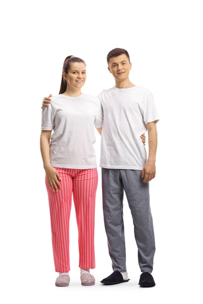 Full length portrait of a young male and female in pajamas posing in embrace isolated on white background - Foto, Imagen