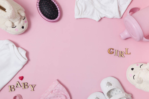 Komposition von oben mit Baby-Accessoires und Kleidern auf farbigem rosa Hintergrund. Rahmen aus Babyzubehör lag flach mit Kopierraum - Foto, Bild