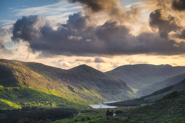 Dramatyczne niebo o zachodzie słońca w Black Valley. Góry MacGillycuddys Reeks oświetlone światłem słonecznym, Pierścień Kerry, Irlandia - Zdjęcie, obraz