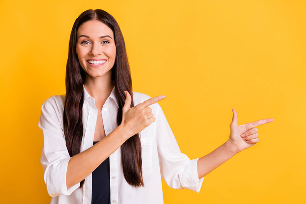Photo of charming cheerful lady beaming smile indicate fingers empty space isolated on yellow color background - Foto, immagini