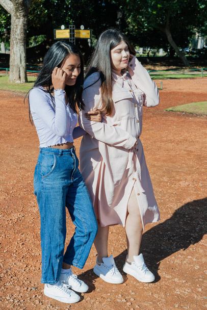 Zwei lateinamerikanische Freundinnen spazieren durch den Park. Freindship-Konzept. - Foto, Bild