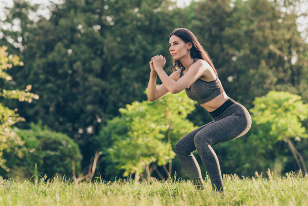 Full size profile photo of pretty girl doing squats look far away enjoy weekend morning workout outdoors - Φωτογραφία, εικόνα