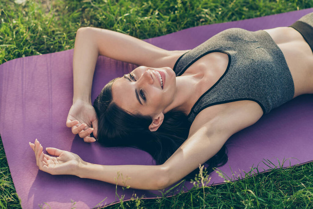 Photo of nice optimistic brunette lady lie down wear sport cloth rest outdoors on grass - Zdjęcie, obraz