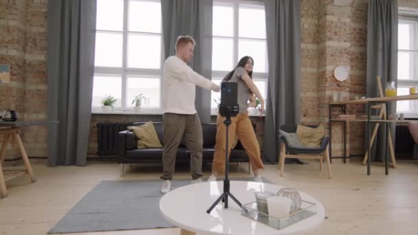 Slowmo εντοπισμό πλάνο του νεαρού άνδρα και της γυναίκας χορεύουν μαζί και κινηματογραφούνται στο κινητό τηλέφωνο σε τρίποδο - Πλάνα, βίντεο