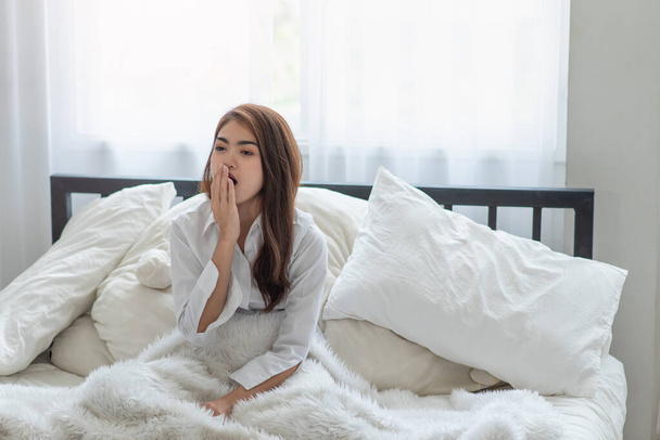 jong aziatische vrouw geeuwen omdat ze is moe terwijl wakker in de ochtend - Foto, afbeelding