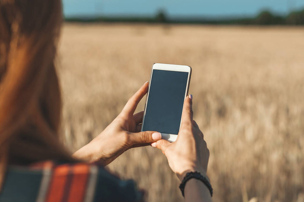 Makieta smartfona w dłoni dziewczyny, na tle pola - Zdjęcie, obraz