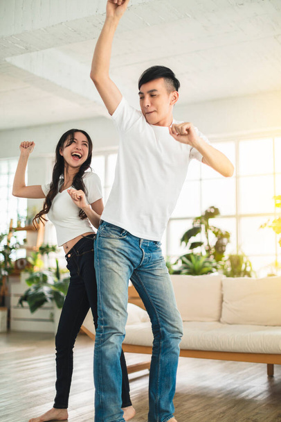 Ευτυχισμένο νεαρό ζευγάρι που χορεύει στο σαλόνι στο σπίτι  - Φωτογραφία, εικόνα