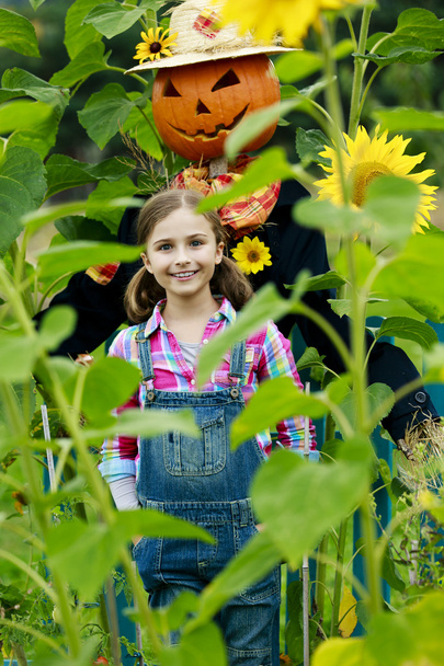 Scarecrow and happy girl  in the garden - Photo, Image