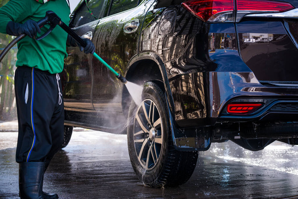 Worker in car wash shop under working to clean customer car by soap form ,car service concept. - Фото, зображення