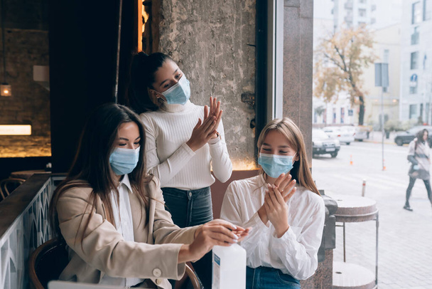 Vrouwen die een antibacterieel antisepticum gebruiken om te desinfecteren in het café. - Foto, afbeelding