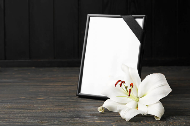 Photo frame and lily flower on dark wooden background - Фото, изображение