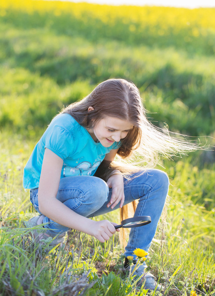 Дівчина зі збільшувальним склом дивиться на квітку
 - Фото, зображення