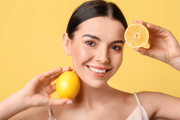 Mooie jonge vrouw met citroenen op kleur achtergrond - Foto, afbeelding