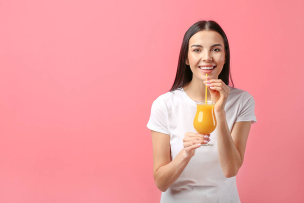Piękna młoda kobieta pije sok pomarańczowy na tle koloru - Zdjęcie, obraz