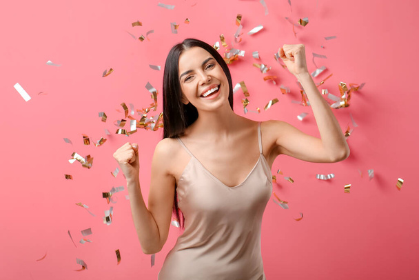 Beautiful young woman and falling confetti on color background - Fotoğraf, Görsel