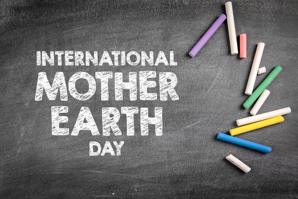 Международный день Матери-Земли 22 апреля. Цветные кусочки мела на темной доске - Фото, изображение