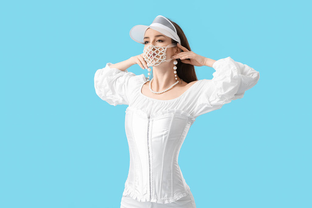 Mulher nova na moda usando máscara no fundo de cor - Foto, Imagem