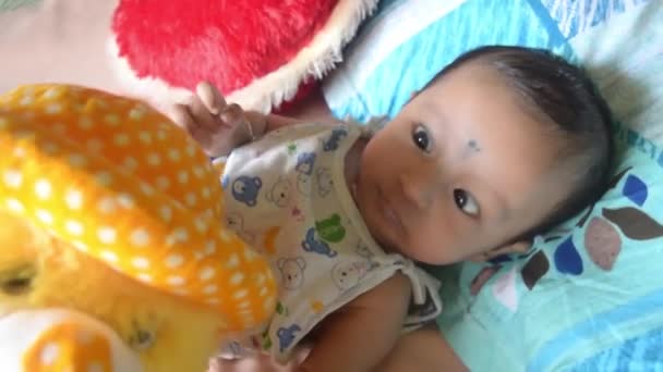テディと赤ちゃんよ。かわいい新生児の男の子とテディベアが家のベッドの上に横たわっています。3ヶ月の甘い小さな幼児クローズアップ肖像画。インドの民族。正面図. - 映像、動画
