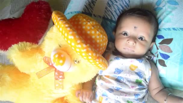 テディと赤ちゃんよ。かわいい新生児の男の子とテディベアが家のベッドの上に横たわっています。3ヶ月の甘い小さな幼児クローズアップ肖像画。インドの民族。正面図. - 映像、動画