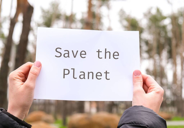 Female hands holding white paper sheet with text SAVE THE PLANET outdoors. Nature background. Protester activist. Lifestyle and activism - Foto, Imagen