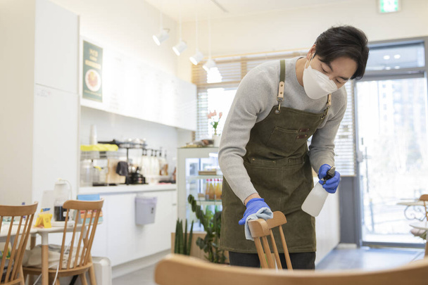 Asian man with mask sanitizing store during covid - Foto, Bild