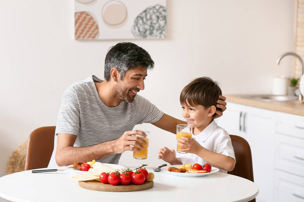 Father and his little son having breakfast in kitchen - Photo, Image