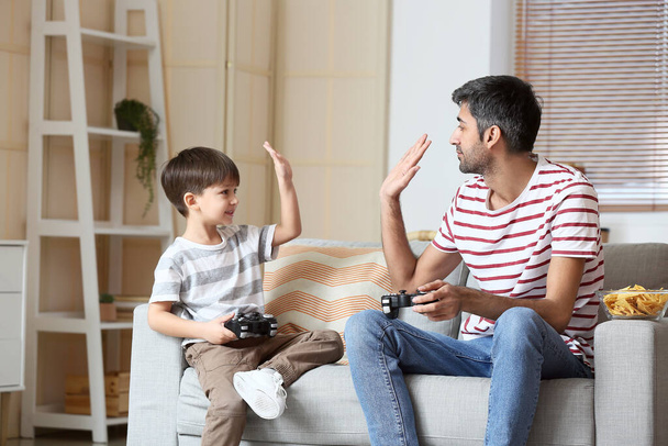 Father and little son playing video games at home - Photo, Image