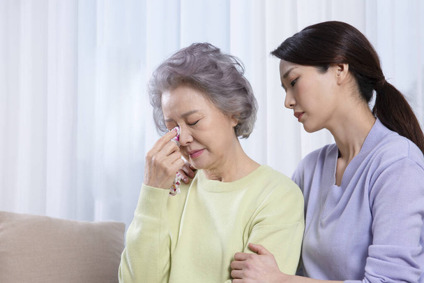 depressed Asian old mother comforted by middle aged daughter - Photo, Image