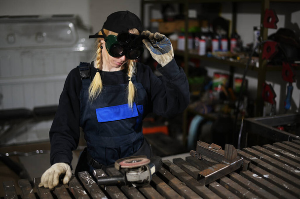 Photo of cute caucasian blonde girl with angle grinder working in glasses - Foto, imagen