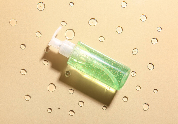 Bottle of cosmetic product on color background with water drops - Foto, immagini