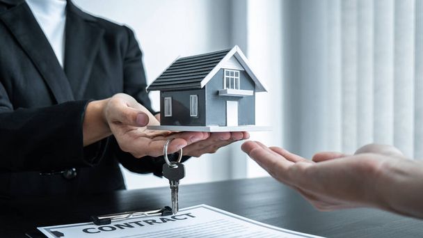 Agent nieruchomości daje dom i klucze do klienta po podpisaniu umowy nieruchomości z zatwierdzonym formularzem wniosku o kredyt hipoteczny lub ubezpieczenia domu. - Zdjęcie, obraz