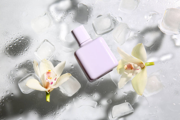 Lahvička parfému, kostky ledu a květiny na skle s kapkami vody - Fotografie, Obrázek