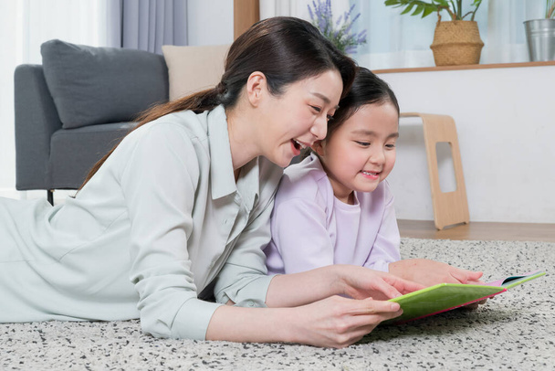 Asian mother and young daughter reading book - 写真・画像